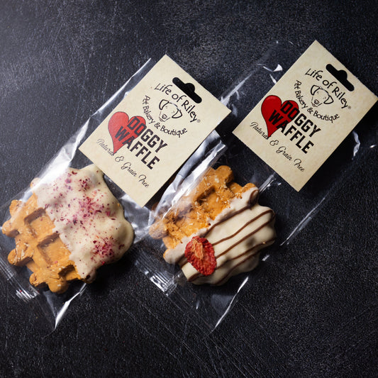 Two packages of dog treats with heart-shaped labels on a dark surface