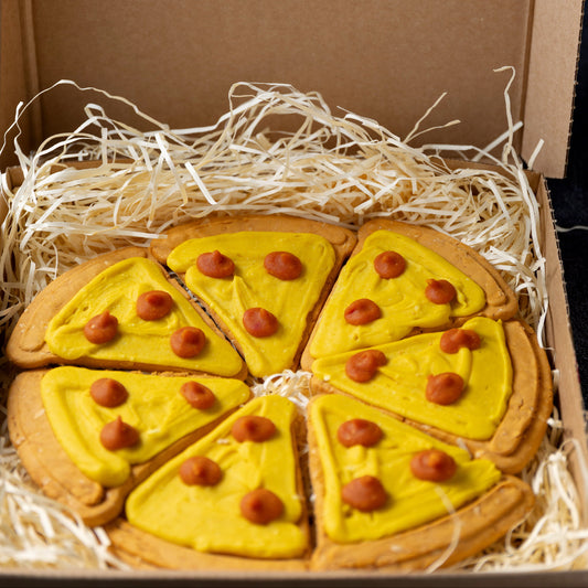 Dog treat shaped like a pizza in a box with 'Life of Riley Pet Bakery & Boutique Pawtisserie' branding.