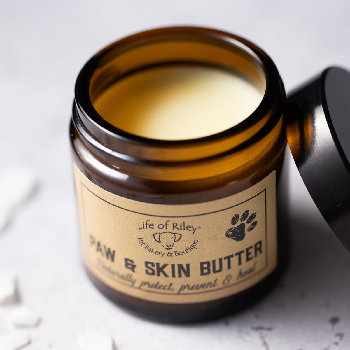 Jar of raw skin butter with a label on a light background