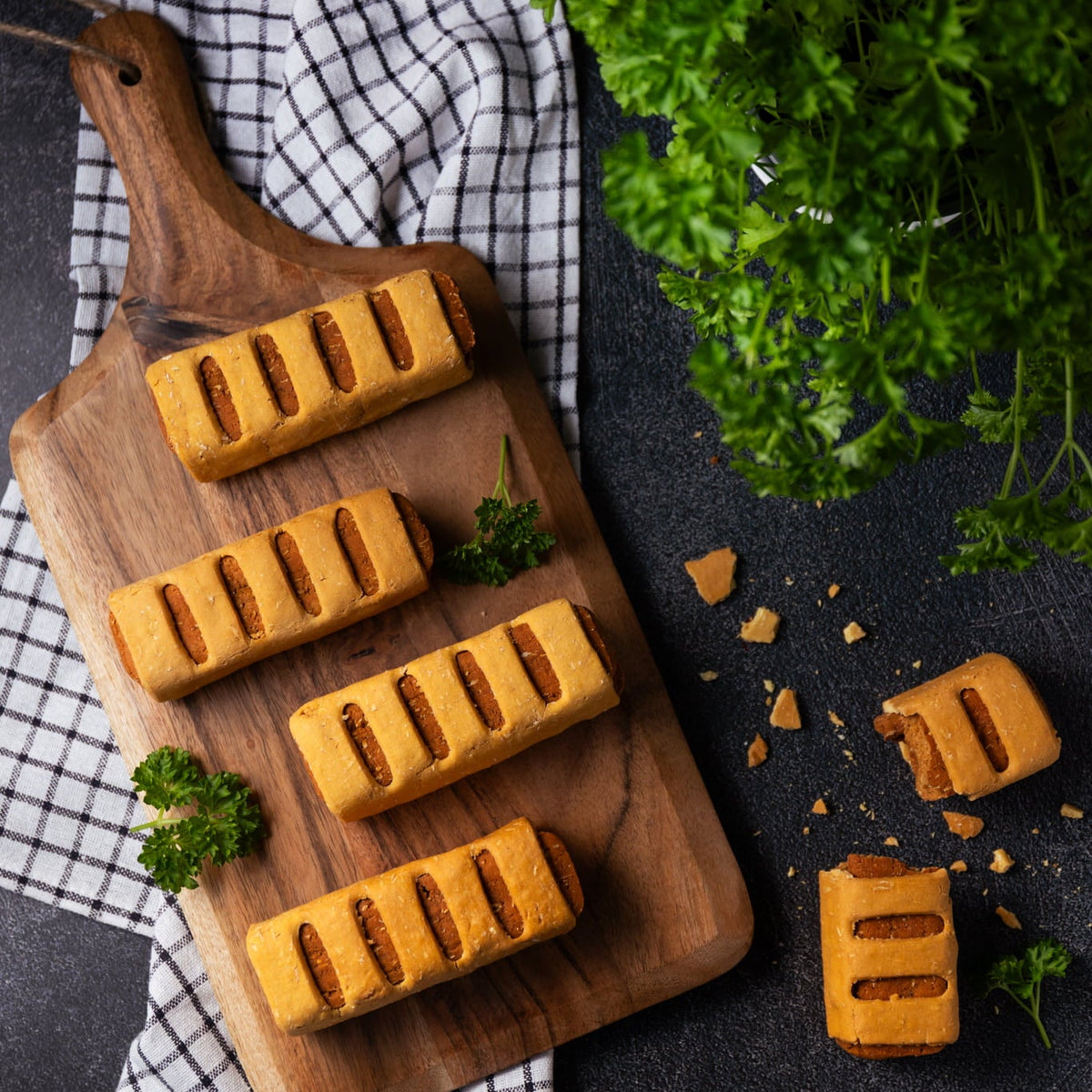 Wooden cutting board with bread slices on a dark surface with herbs
