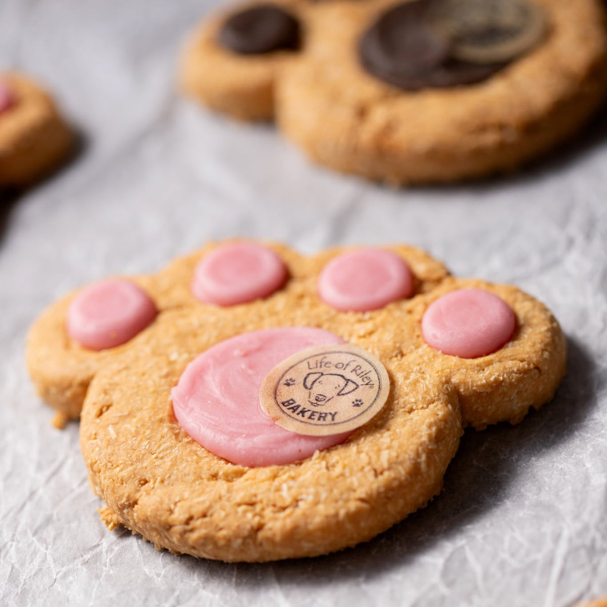 Dog paw-shaped cookies with pink pads on a gray surface
